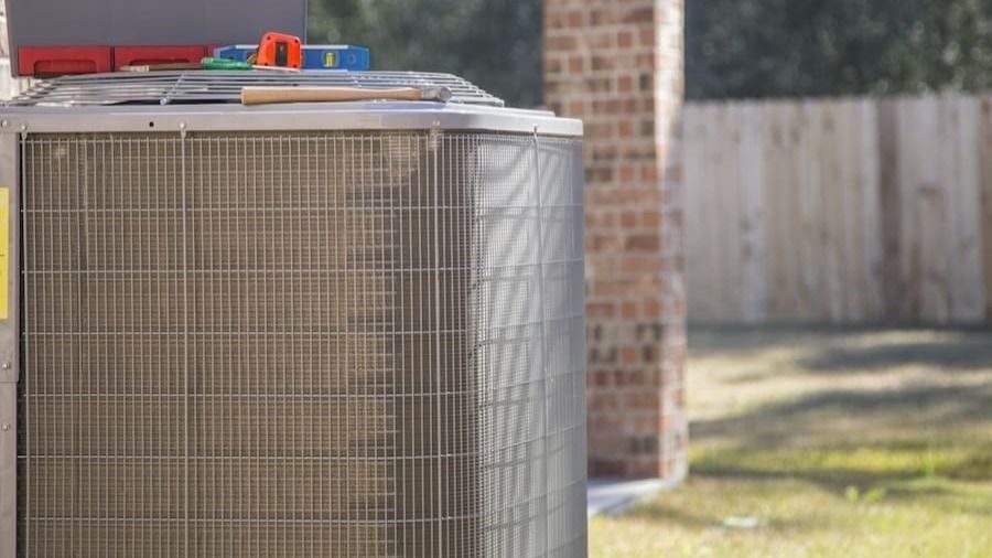 Air conditioner outside a home with maintenance tools on top of it
